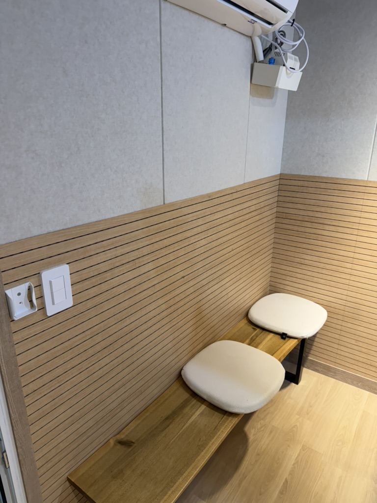 흡음 벽면 아래 원목 벤치와 방석